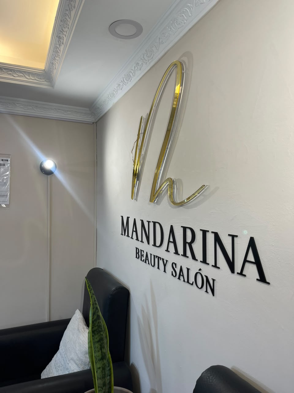 Detalle del logo Mandarina Beauty Salón en la pared del interior del local